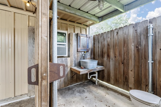 bathroom with wooden walls and unfinished concrete flooring