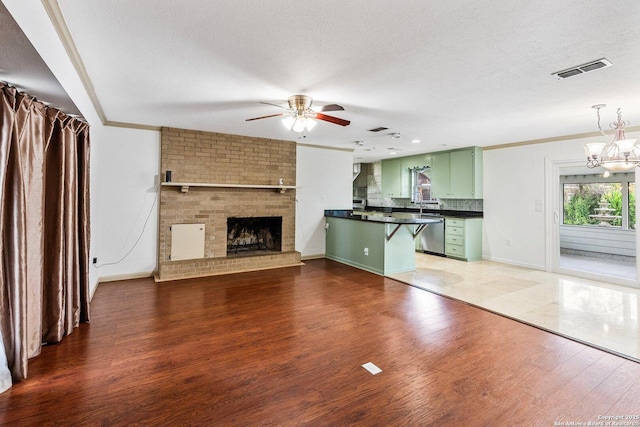 unfurnished living room featuring visible vents, dark wood-style flooring, a textured ceiling, crown molding, and a fireplace