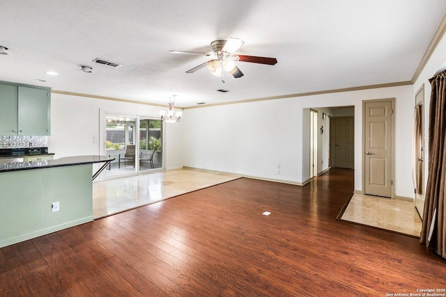 unfurnished living room with dark wood-style floors, crown molding, baseboards, and ceiling fan with notable chandelier