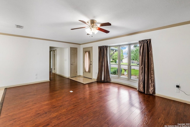 unfurnished room featuring dark wood-style floors, crown molding, visible vents, ceiling fan, and baseboards