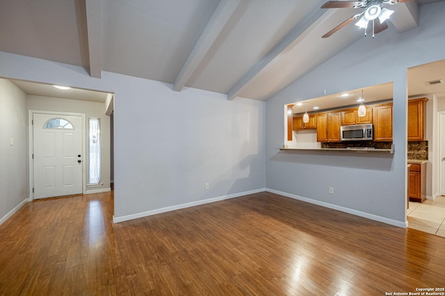 unfurnished living room with wood finished floors, visible vents, baseboards, lofted ceiling with beams, and ceiling fan