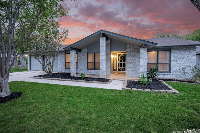 rear view of property featuring a yard, an attached garage, and stone siding