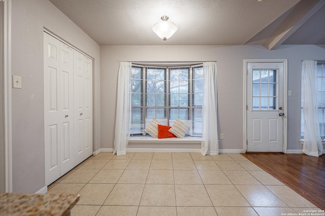 entryway with baseboards, a textured ceiling, and light tile patterned floors
