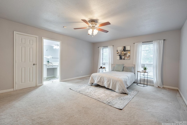 bedroom featuring light carpet, connected bathroom, baseboards, a textured ceiling, and ceiling fan