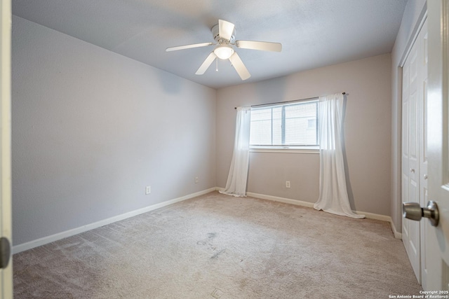 empty room featuring carpet, a ceiling fan, and baseboards