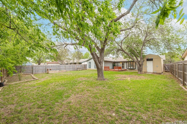 view of yard with a fenced backyard, an outdoor structure, a wooden deck, and a storage shed