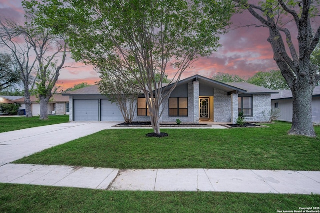 mid-century inspired home with a lawn, an attached garage, and driveway