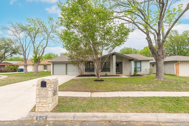 mid-century inspired home featuring brick siding, an attached garage, a front yard, and concrete driveway