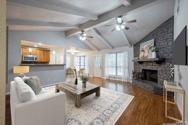 living room with a ceiling fan, vaulted ceiling with beams, a fireplace, baseboards, and dark wood-style flooring