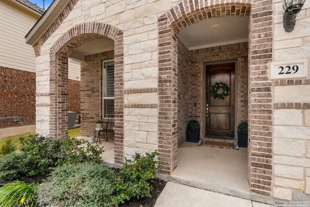 view of exterior entry with a porch and brick siding