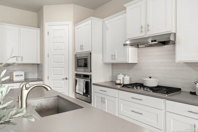 kitchen featuring appliances with stainless steel finishes, a sink, white cabinetry, and under cabinet range hood