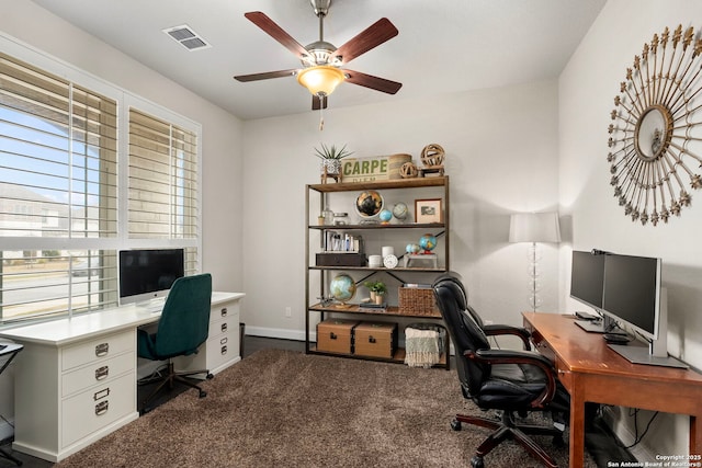 home office featuring ceiling fan, dark colored carpet, visible vents, and baseboards