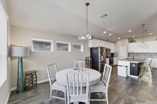 dining space featuring lofted ceiling, wood tiled floor, visible vents, and baseboards