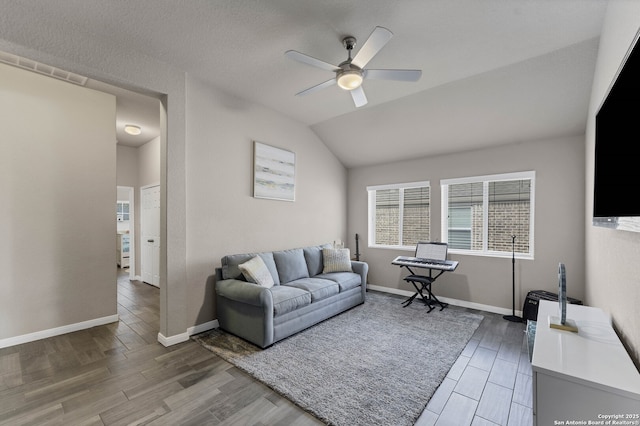 living room featuring a ceiling fan, vaulted ceiling, baseboards, and wood finished floors