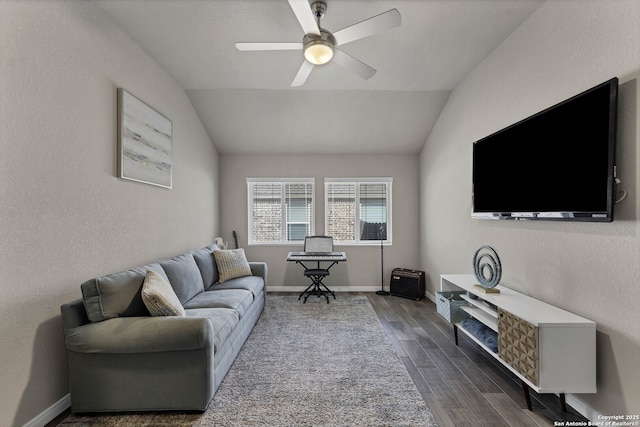 living area featuring baseboards, a textured wall, dark wood-style floors, ceiling fan, and vaulted ceiling