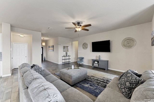 living room featuring baseboards, visible vents, a ceiling fan, and wood finished floors