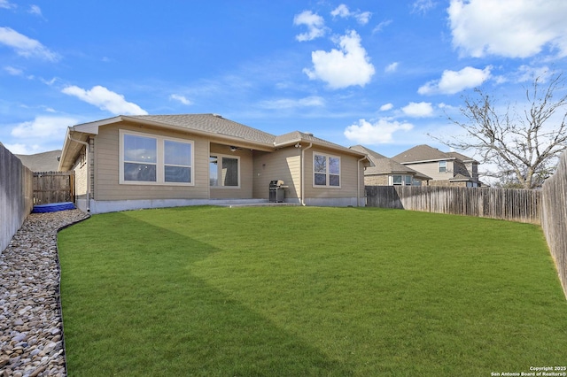 rear view of house featuring a yard and a fenced backyard