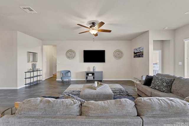 living area featuring baseboards, visible vents, dark wood finished floors, and a ceiling fan