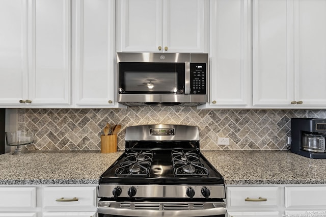 kitchen with appliances with stainless steel finishes, white cabinets, light stone counters, and tasteful backsplash