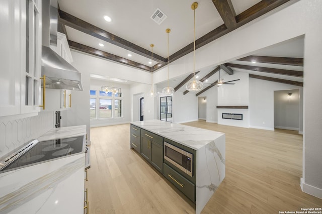 kitchen with hanging light fixtures, light stone counters, white cabinets, and open floor plan