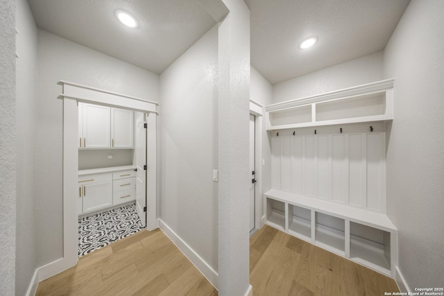 mudroom with light wood finished floors, a textured wall, baseboards, and recessed lighting