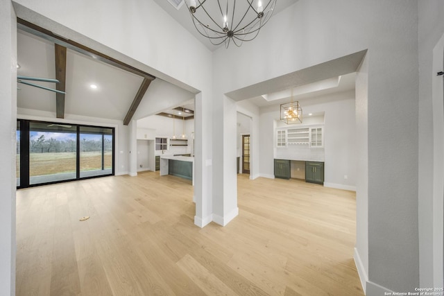 unfurnished living room with baseboards, light wood-style flooring, an inviting chandelier, high vaulted ceiling, and beam ceiling