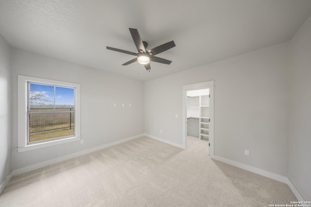 spare room featuring baseboards, a ceiling fan, and light colored carpet