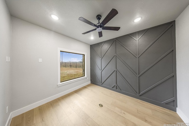 unfurnished room featuring baseboards, a ceiling fan, wood finished floors, a decorative wall, and recessed lighting