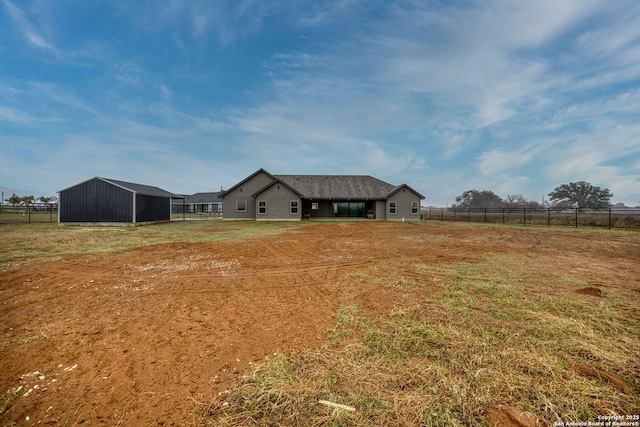 view of yard with an outbuilding, a rural view, and fence