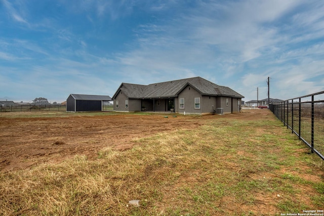 exterior space with central AC unit, a rural view, fence, and a yard