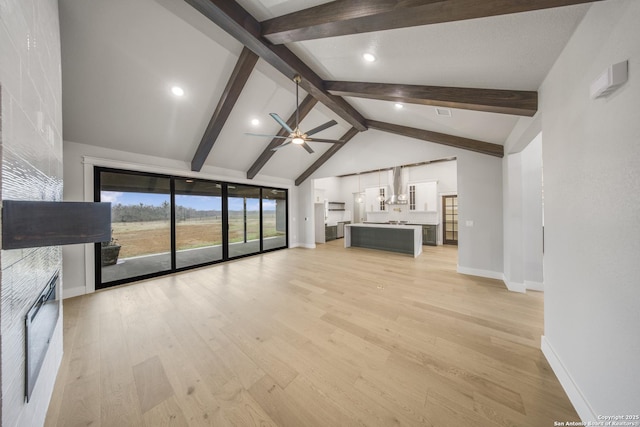 unfurnished living room featuring baseboards, ceiling fan, beamed ceiling, light wood-type flooring, and a fireplace