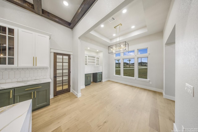 unfurnished living room with baseboards, visible vents, a tray ceiling, light wood-style floors, and recessed lighting