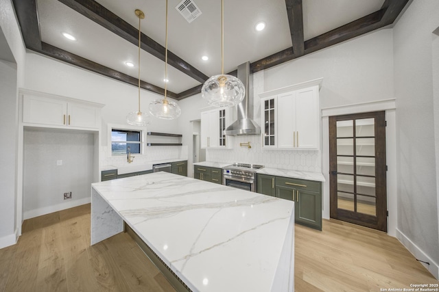 kitchen with visible vents, white cabinets, wall chimney exhaust hood, a large island, and pendant lighting