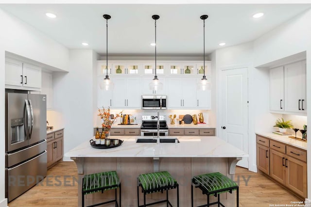 kitchen featuring appliances with stainless steel finishes, white cabinetry, glass insert cabinets, and a center island with sink