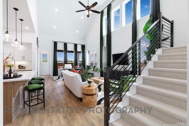 living area featuring dark wood-style floors, plenty of natural light, stairway, and high vaulted ceiling