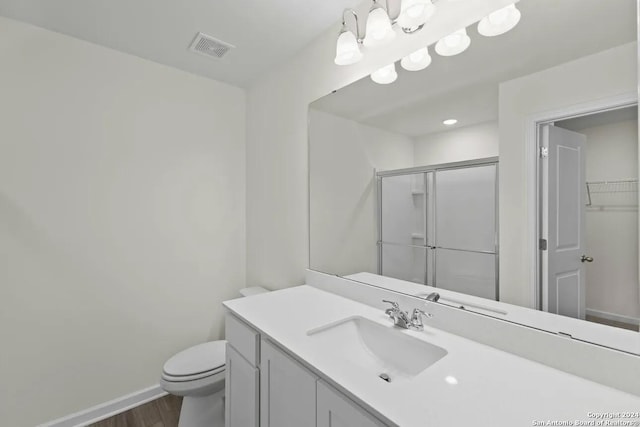 full bath with wood finished floors, vanity, visible vents, baseboards, and a shower stall