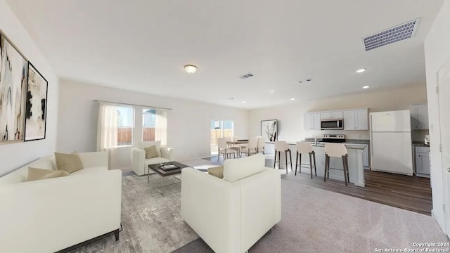 living room with light wood-type flooring, recessed lighting, and visible vents