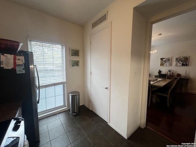 interior space featuring dark tile patterned flooring, visible vents, and baseboards