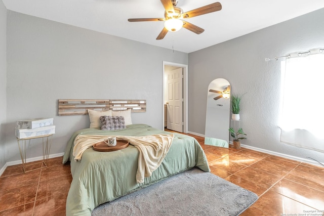 tiled bedroom featuring baseboards and a ceiling fan