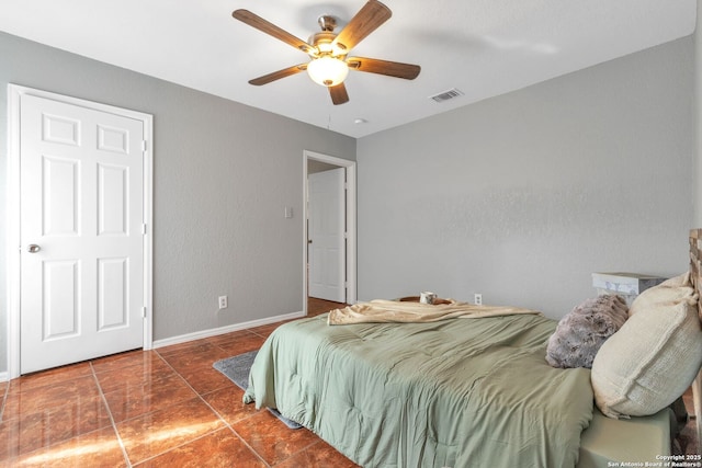 bedroom with a ceiling fan, dark tile patterned floors, visible vents, and baseboards