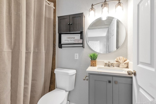 full bath featuring a textured wall, a shower with shower curtain, vanity, and toilet