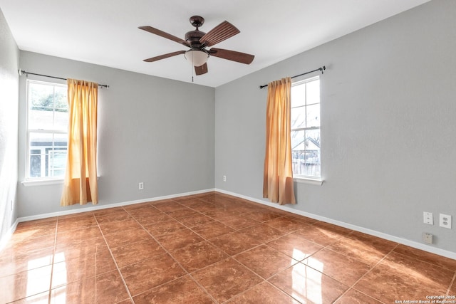 unfurnished room featuring ceiling fan, dark tile patterned floors, and baseboards