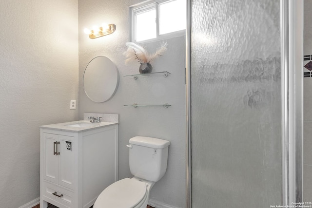 full bathroom featuring toilet, a textured wall, an enclosed shower, and vanity