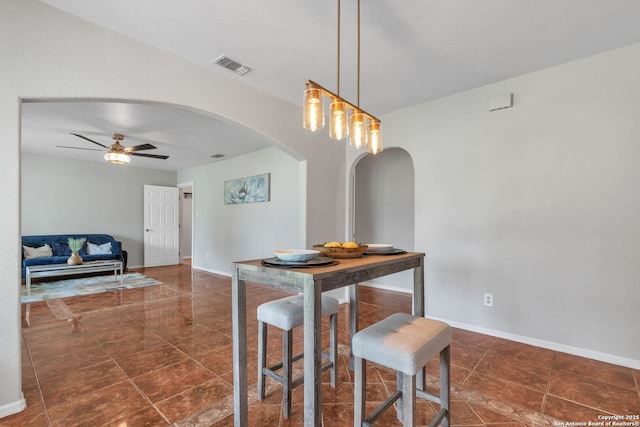 dining area with baseboards, visible vents, arched walkways, and a ceiling fan