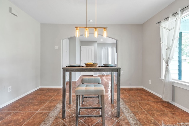 dining space featuring dark tile patterned flooring and baseboards