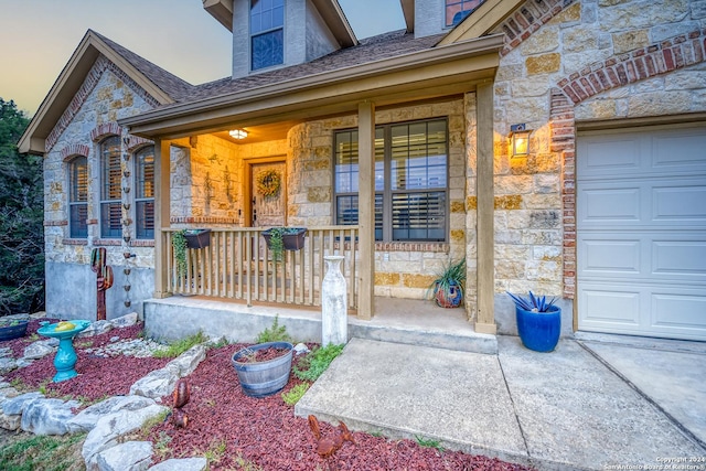 property entrance with a garage, stone siding, and a porch