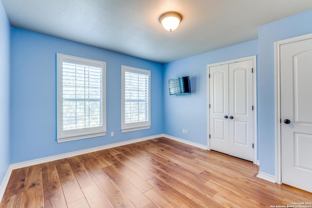 unfurnished bedroom featuring light wood-style floors, a closet, and baseboards