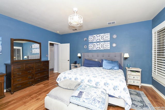 bedroom with visible vents, baseboards, and wood finished floors