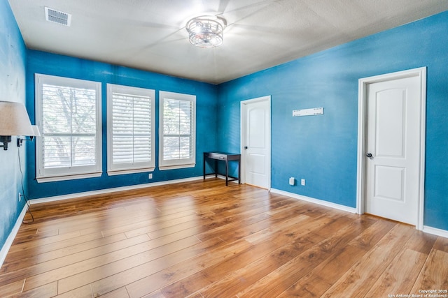 unfurnished room with visible vents, baseboards, and wood finished floors