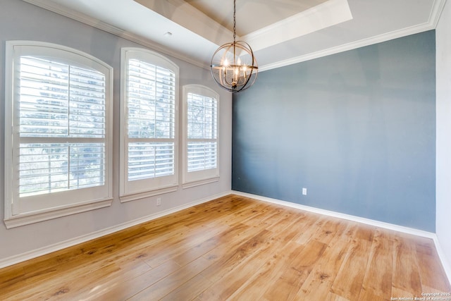 empty room featuring ornamental molding, a raised ceiling, and wood finished floors